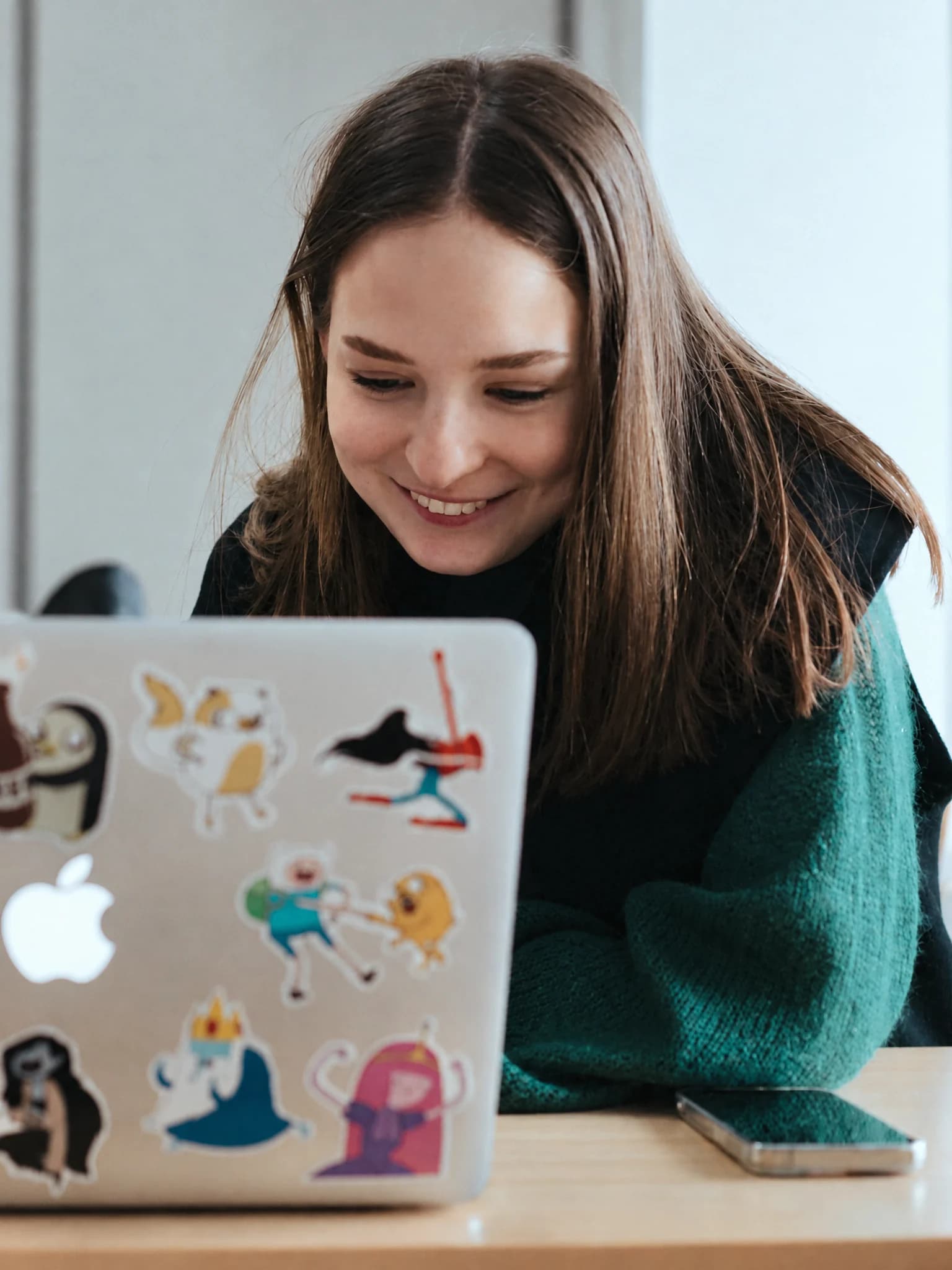 Student smiling at a laptop in a classroom